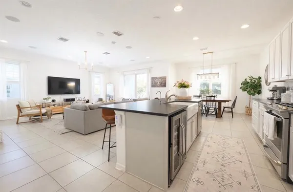 a kitchen with stainless steel appliances granite countertop a stove top oven a sink dishwasher a dining table and chairs with wooden floor