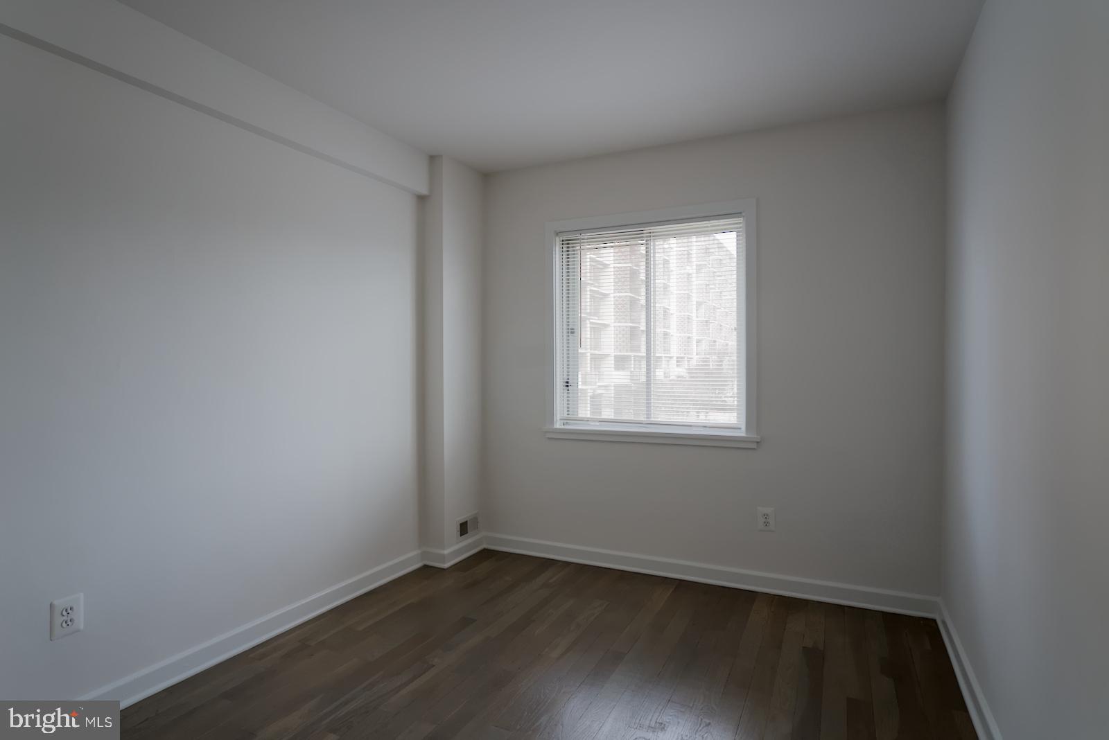301 I Street Southwest, Unit 108 Washington, DC 20024 - Photo 21 of 66 an empty room with wooden floor and windows