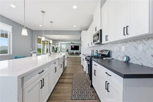 a large white kitchen with stainless steel appliances lots of counter space and window