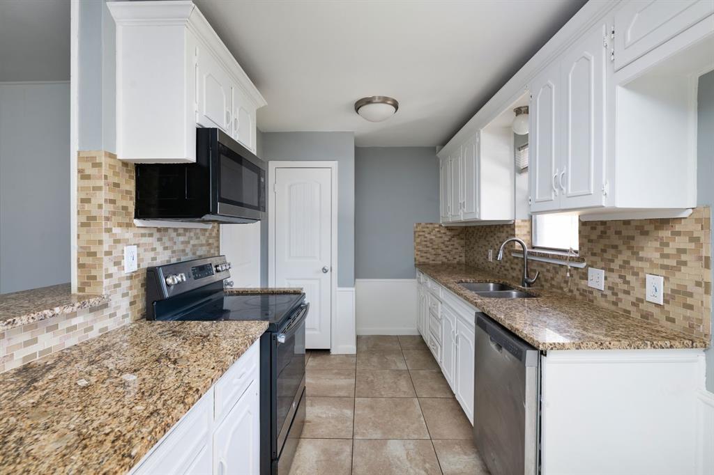 540 Billie Ruth Lane Hurst, TX 76053 - Photo 11 of 40 Kitchen featuring stainless steel appliances, tasteful backsplash, light stone counters, and white cabinets