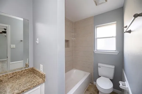 a bathroom with a granite countertop toilet and a bathtub