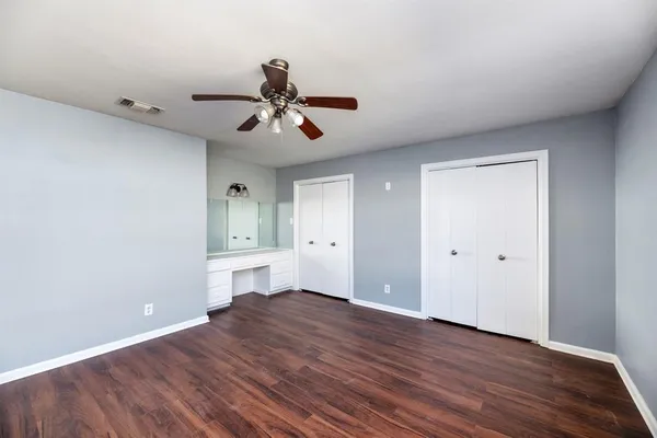 a view of empty room with wooden floor and ceiling fan