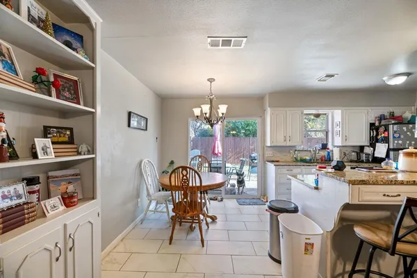 a kitchen with stainless steel appliances kitchen island granite countertop a table chairs and a refrigerator