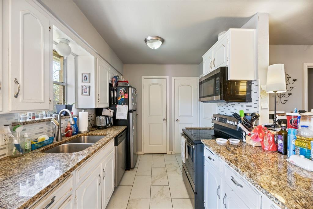 540 Billie Ruth Lane Hurst, TX 76053 - Photo 31 of 40 Kitchen featuring appliances with stainless steel finishes, backsplash, white cabinets, and light stone countertops