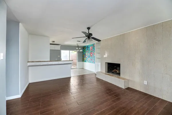 a view of an empty room with wooden floor a fireplace and a window