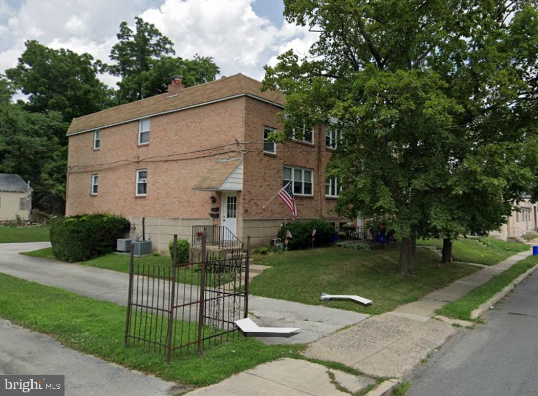 a view of a white house next to a yard with big trees