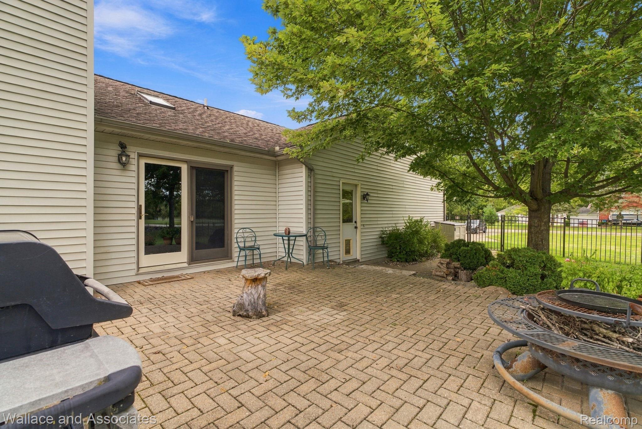 17076 27 Mile Road Ray, MI 48096 - Photo 60 of 63 Expansive paver patio with a sliding glass door entry, exterior lighting fixture, and mature landscaping