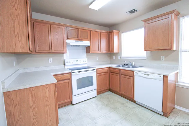 a kitchen with cabinets appliances a sink and a window