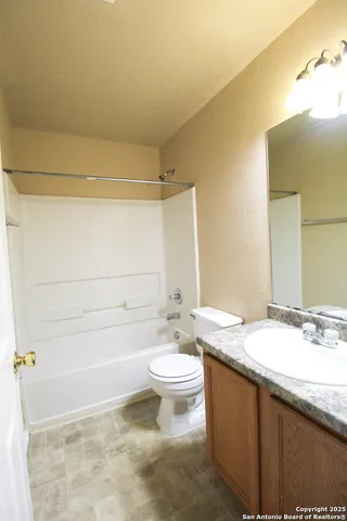a bathroom with a granite countertop sink a toilet a mirror and vanity