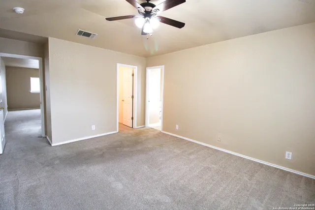 an empty room with windows and fan