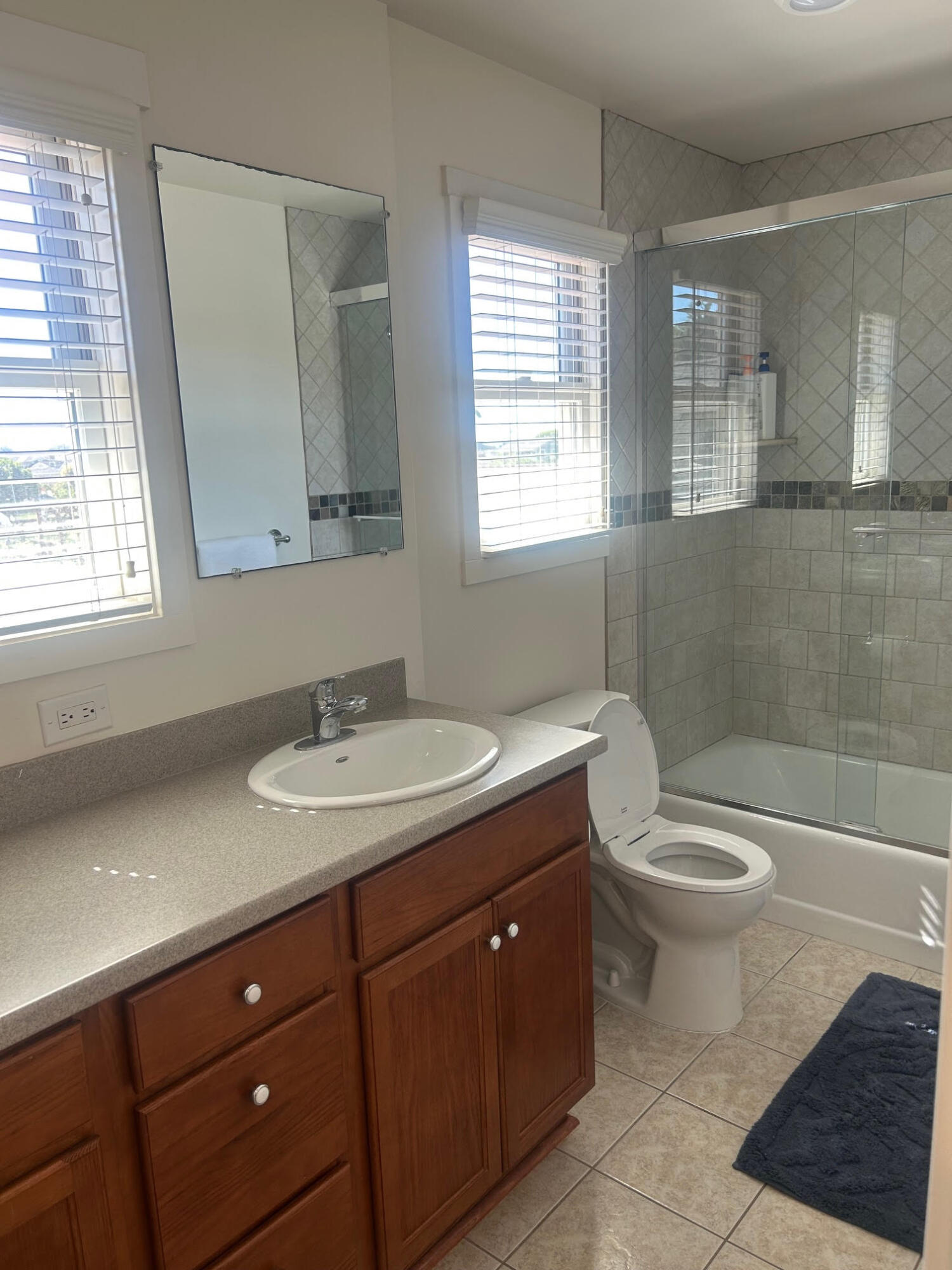 4858 5th Street Carpinteria, CA 93013 - Photo 6 of 10 a bathroom with a granite countertop toilet a sink a mirror a window and a shower