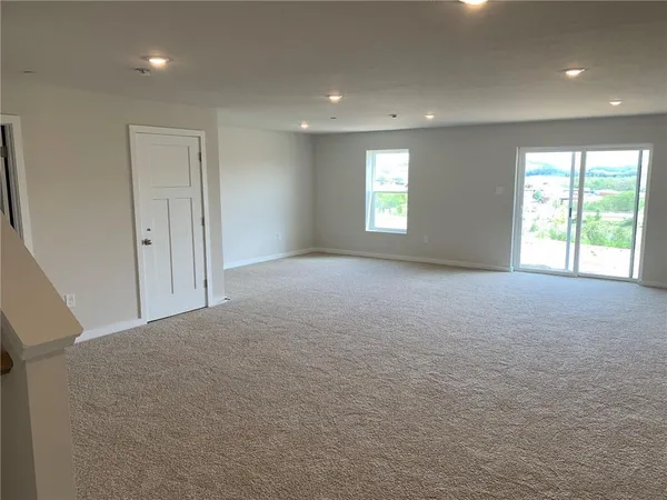 a view of a big room with windows and chandelier fan
