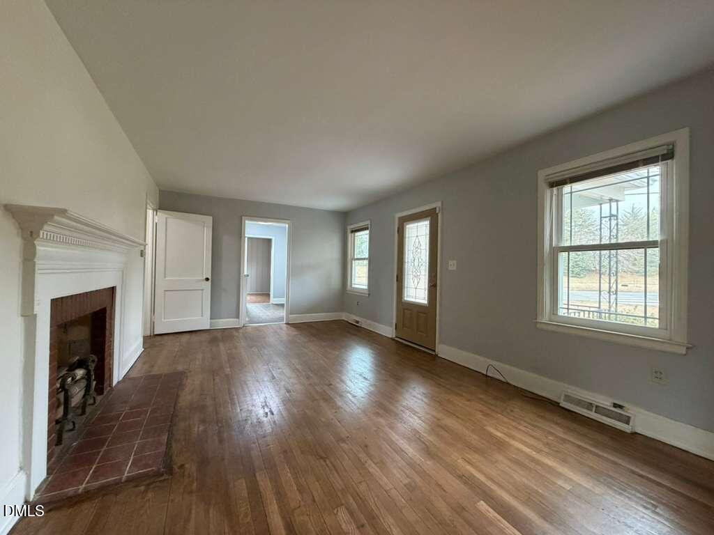 1419 Leon Street Durham, NC 27705 - Photo 19 of 23 an empty room with wooden floor fireplace and windows