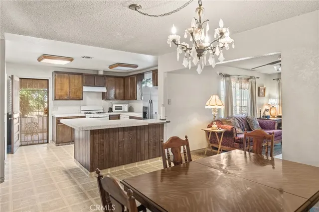 a open kitchen with stainless steel appliances granite countertop a stove dining table chairs and a chandelier