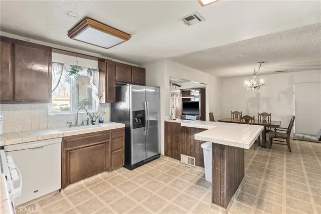 a kitchen with stainless steel appliances a sink a stove a refrigerator cabinets and chairs