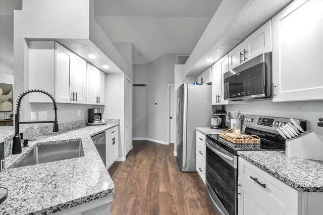 a kitchen with stainless steel appliances granite countertop a sink stove microwave and refrigerator