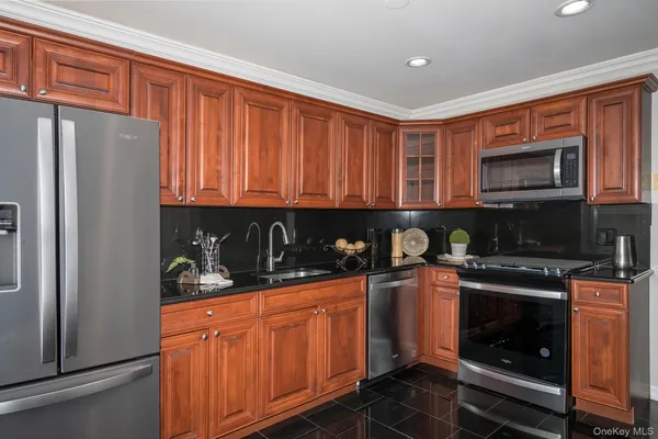 a kitchen with stainless steel appliances granite countertop wooden cabinets a stove a sink and a microwave