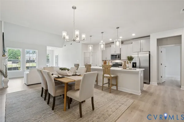 a view of a dining room and livingroom with furniture a rug a fireplace and a chandelier