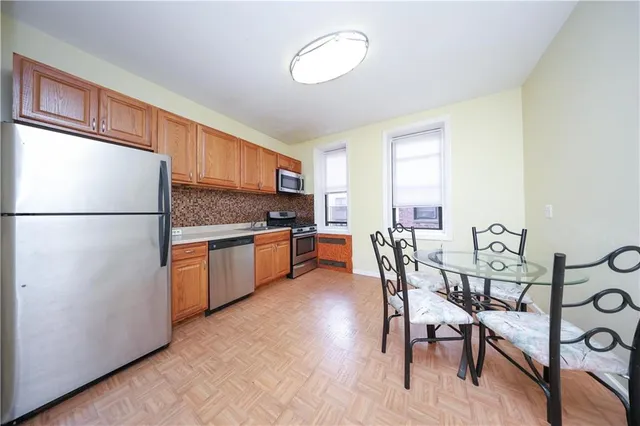 a kitchen with stainless steel appliances granite countertop a refrigerator a stove a sink with a dining table and chairs