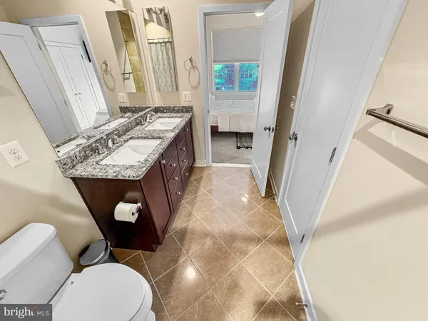 a bathroom with a granite countertop toilet sink and mirror