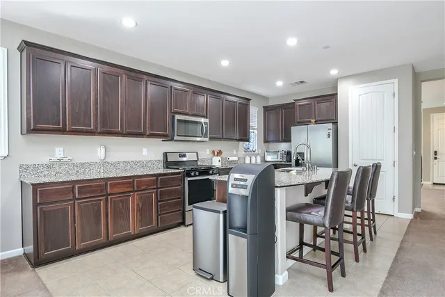 a kitchen with stainless steel appliances granite countertop a stove top oven a sink dishwasher a dining table and chairs