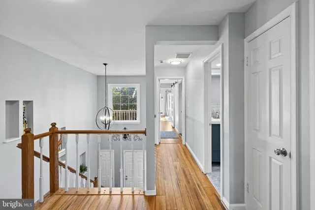 a view of a hallway with wooden floor and stairs