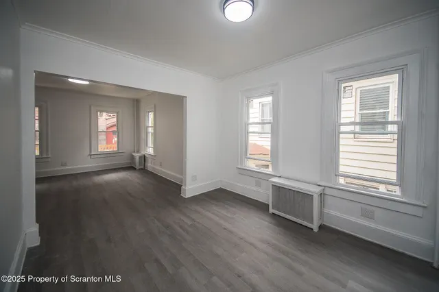 a view of empty room with window and wooden floor