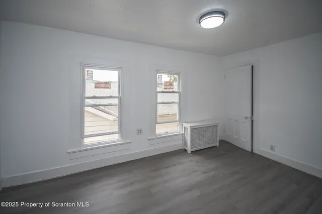 an empty room with wooden floor and window