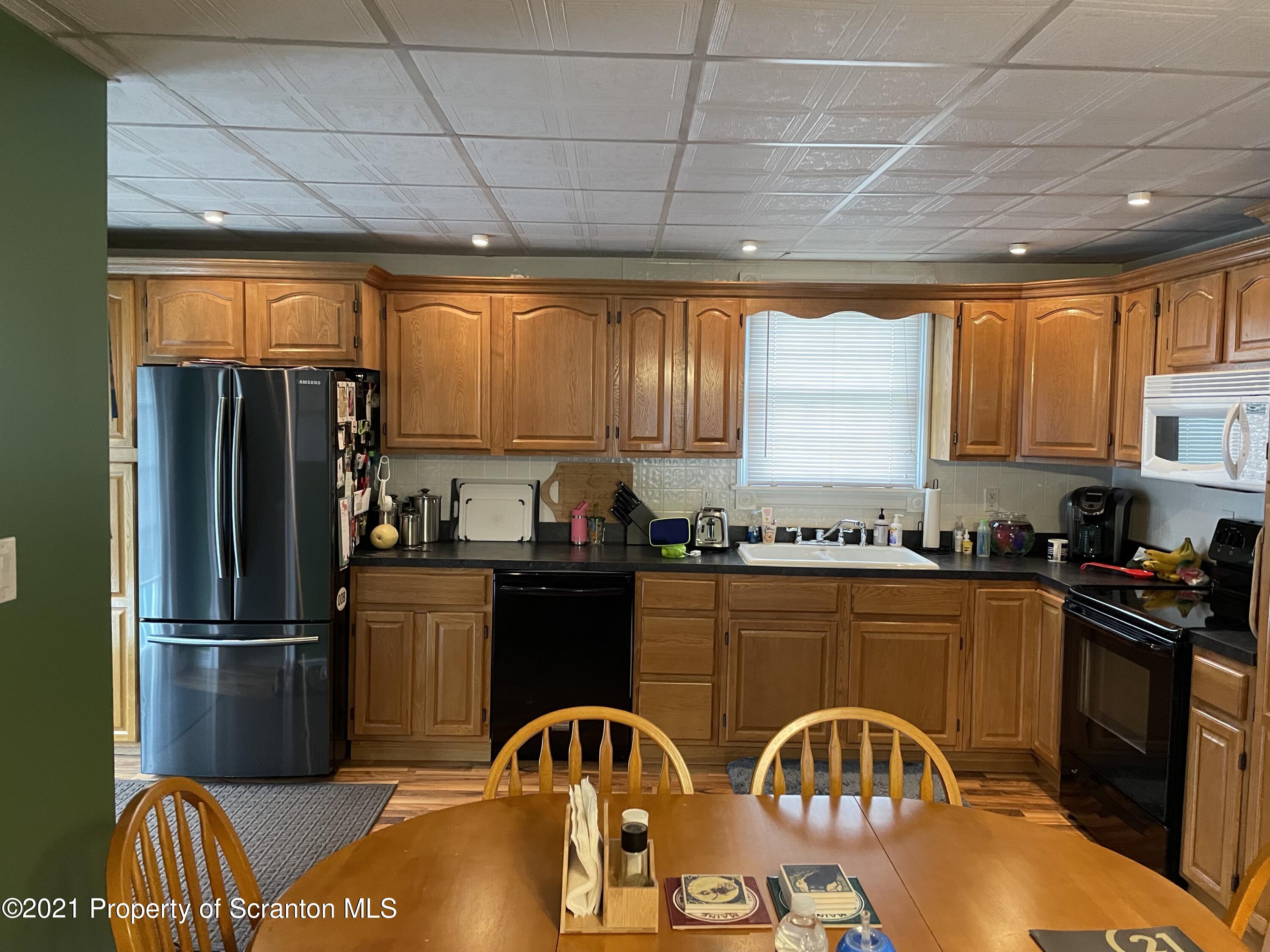 425 Clinton Street Vandling, PA 18421 - Photo 5 of 32 a kitchen with granite countertop a refrigerator and wooden cabinets