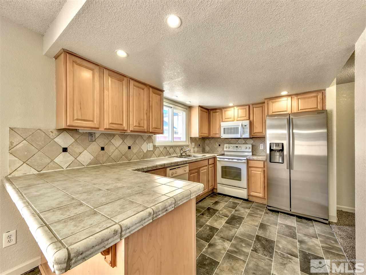 7460 Berryhill Drive Reno, NV 89511 - Photo 6 of 23 a kitchen with stainless steel appliances granite countertop a stove a sink and a refrigerator