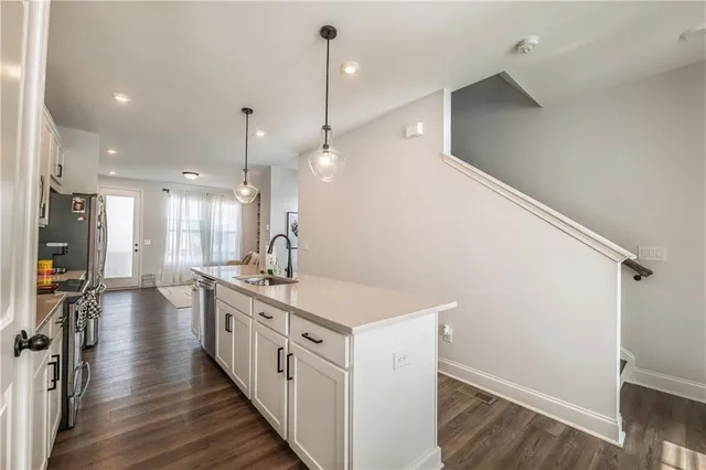 a kitchen with stainless steel appliances a stove a sink a refrigerator and a wooden floor