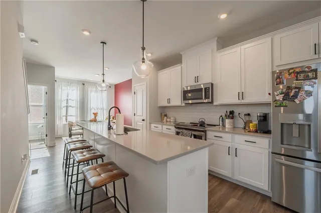 a kitchen with granite countertop a stove a sink dishwasher a refrigerator and white cabinets with wooden floor