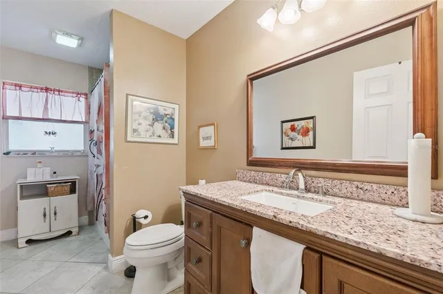 a bathroom with a granite countertop sink mirror vanity and toilet
