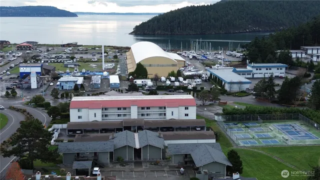 a view of a patio with table and chairs under an umbrella with a barbeque grill and plants
