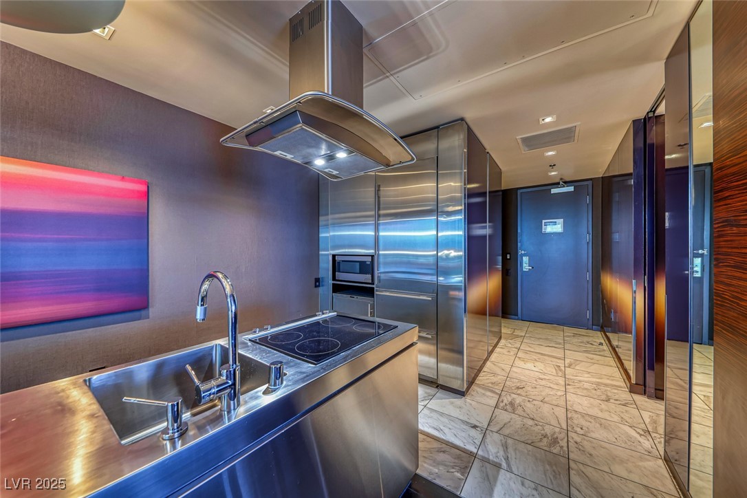 4381 West Flamingo Road, Unit 901 Las Vegas, NV 89103 - Photo 3 of 58 Kitchen with island exhaust hood, light marble finish floors, modern cabinets, stainless steel microwave, and black electric cooktop
