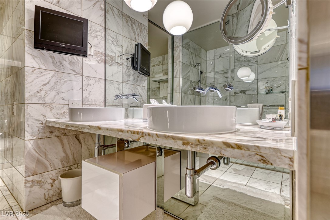 4381 West Flamingo Road, Unit 901 Las Vegas, NV 89103 - Photo 31 of 58 Bathroom featuring tile walls, walk in shower, and a sink