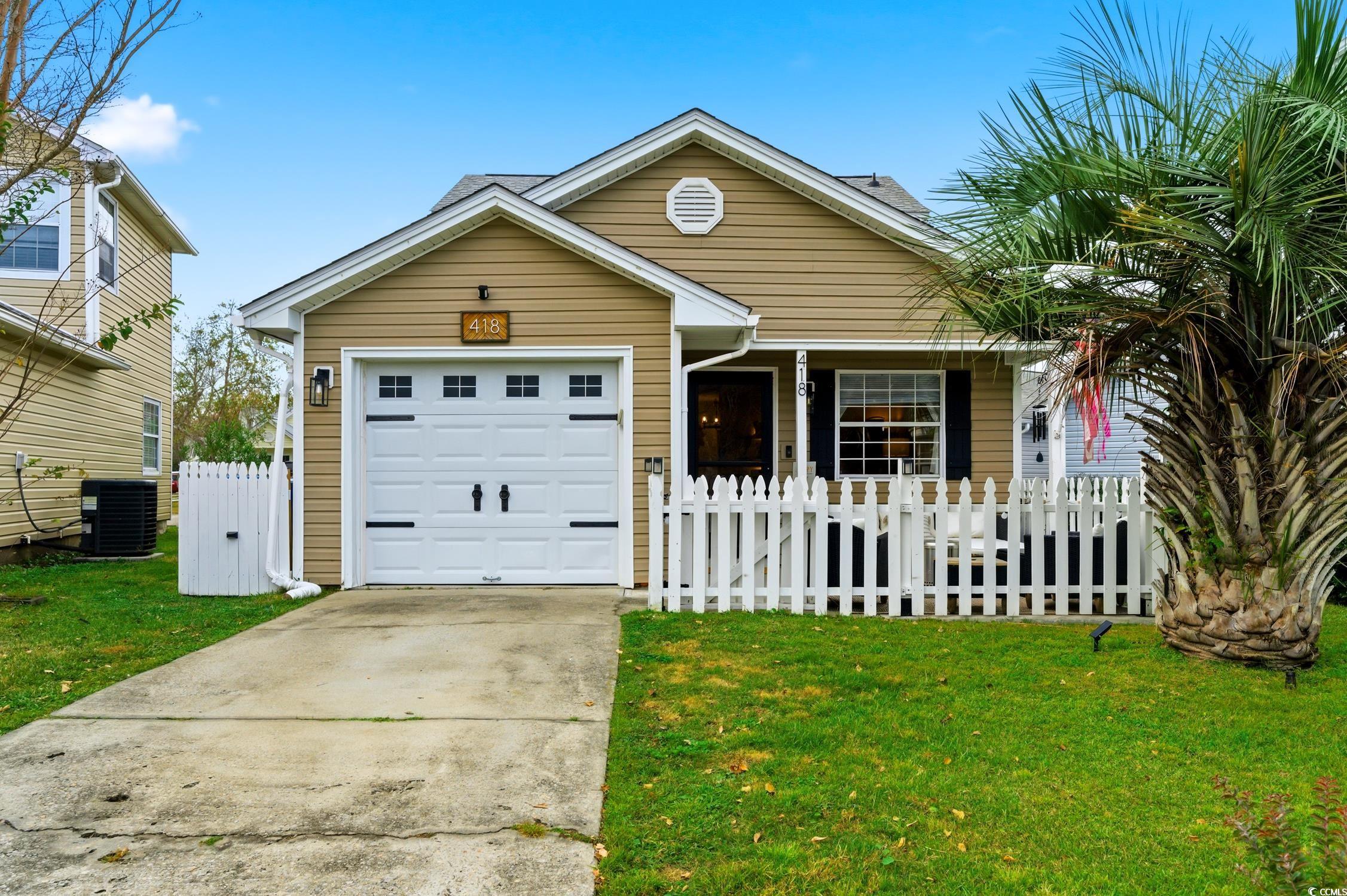 View of front of property featuring a fenced front yard, concrete driveway, an attached garage, and a porch