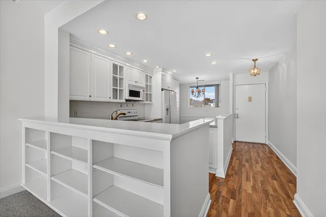 a large white kitchen with stainless steel appliances kitchen island granite countertop a sink and cabinets