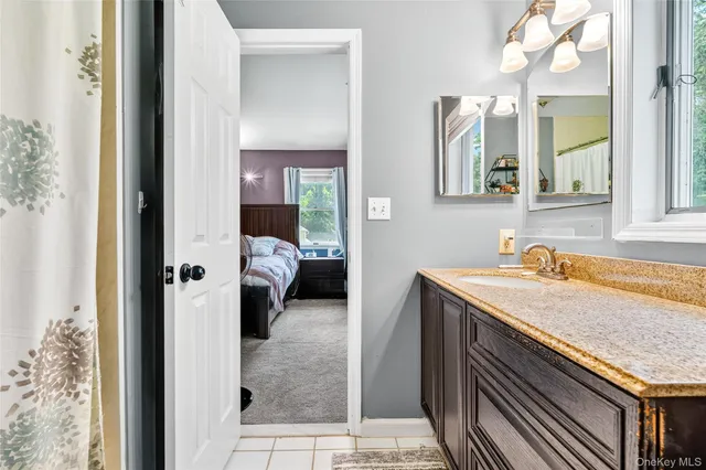 a en suite bathroom with a granite countertop sink and a mirror