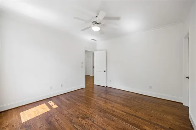 an empty room with wooden floor and fan