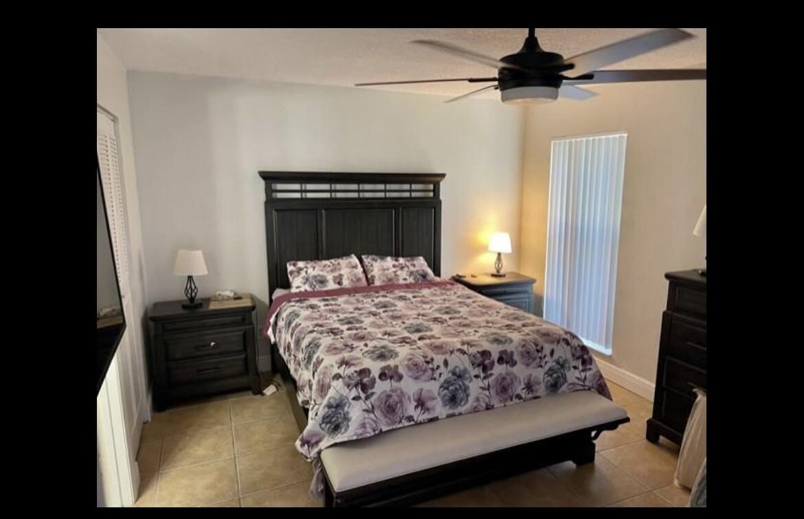107 Bent Arrow Drive, Unit D Jupiter, FL 33458 - Photo 6 of 15 a bedroom with a bed and a chandelier