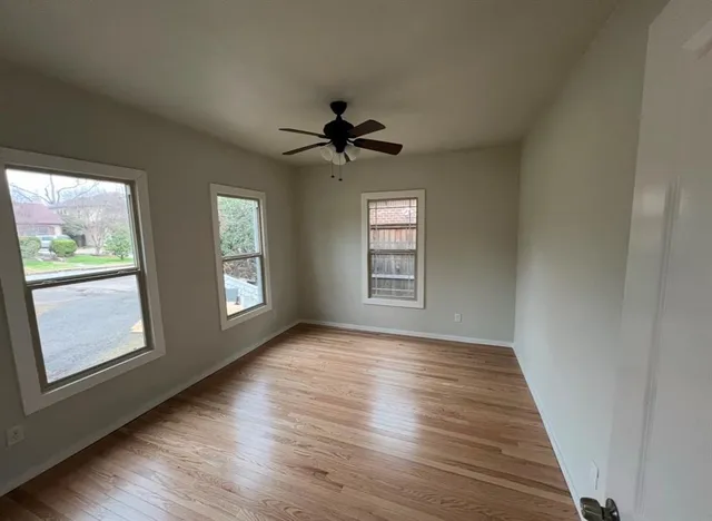 a view of an empty room with a window and wooden floor