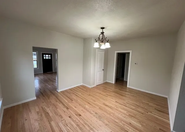 a view of a hallway with wooden floor and chandelier