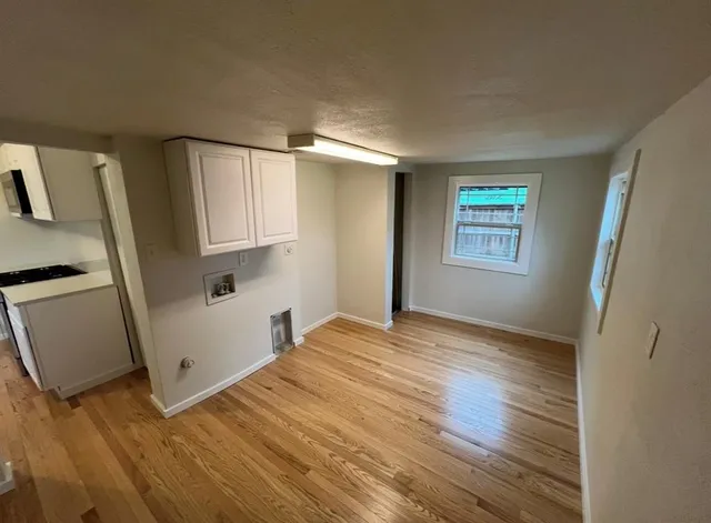 a view of empty room with wooden floor and window