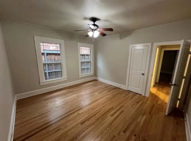 a view of empty room with wooden floor and fan