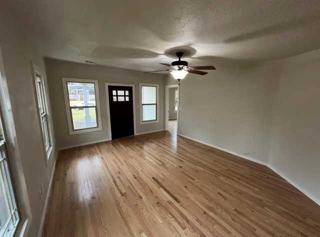a view of an empty room with glass door and wooden floor