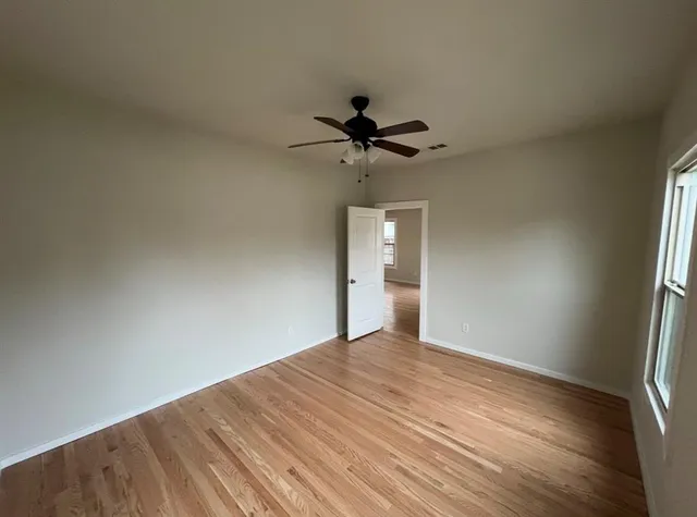 a view of a room with a wooden floor and a ceiling fan