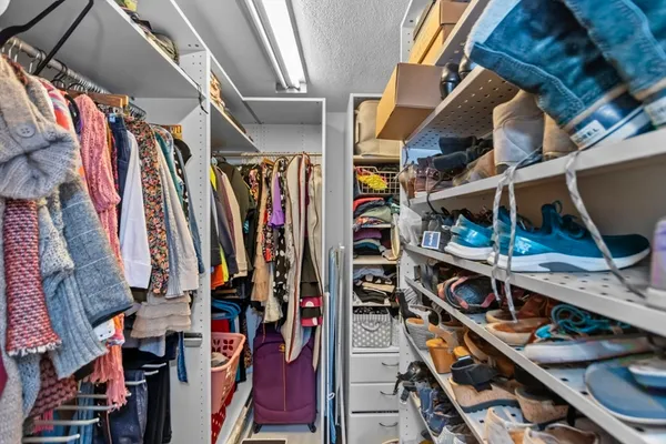 a view of walk in closet with clothes and shoes