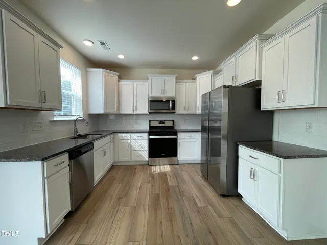 a kitchen with a refrigerator stove top oven and sink