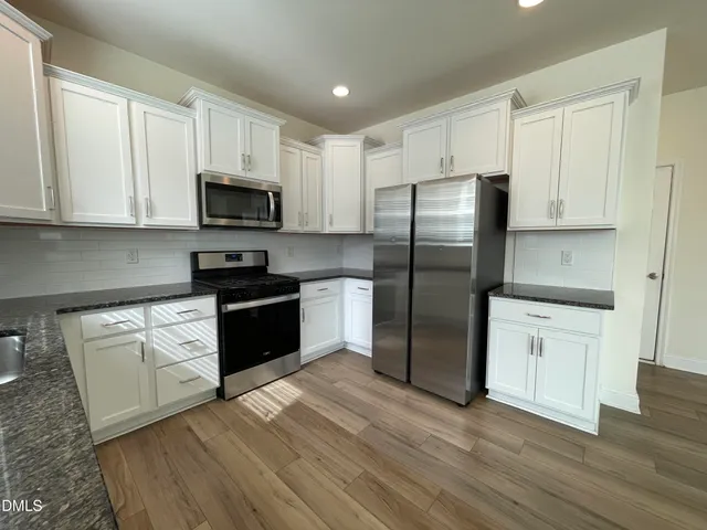 a kitchen with stainless steel appliances granite countertop a stove a sink and white cabinets